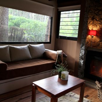 Cabaña Calma: living con ventanales al bosque y hogar a leña